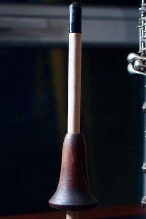 Wooden oboe stand with an oboe on a dark surface